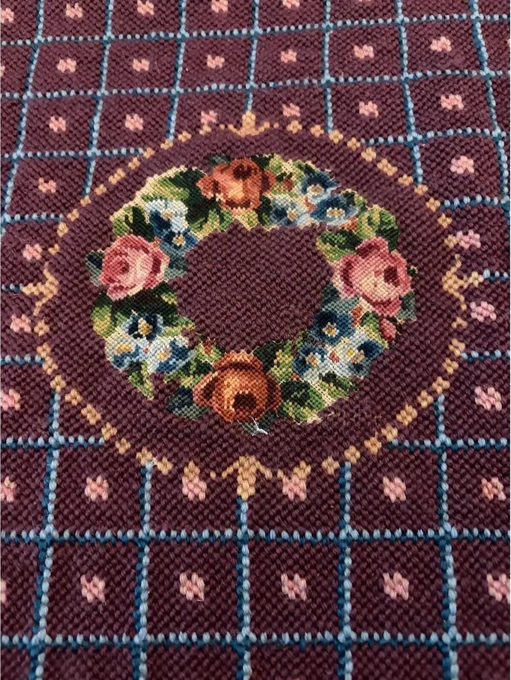 needlepoint tapestry featuring a wreath and geometric pattern.